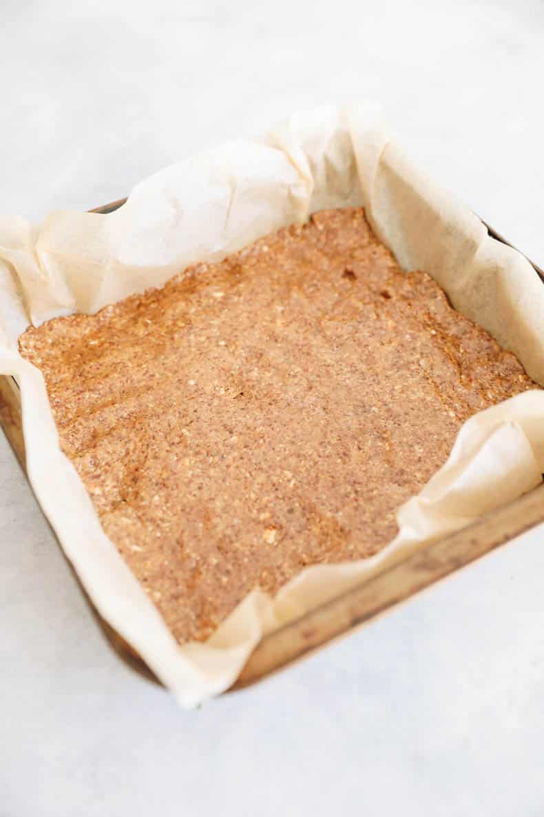 almond butter bar base in a pan with parchment paper.