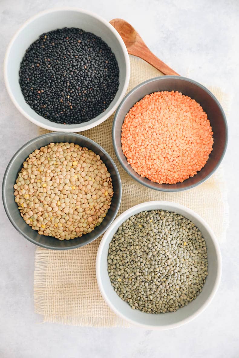 Overhead image of 4 types of lentils - baluga lentils, red lentils, brown lentils and french lentils.