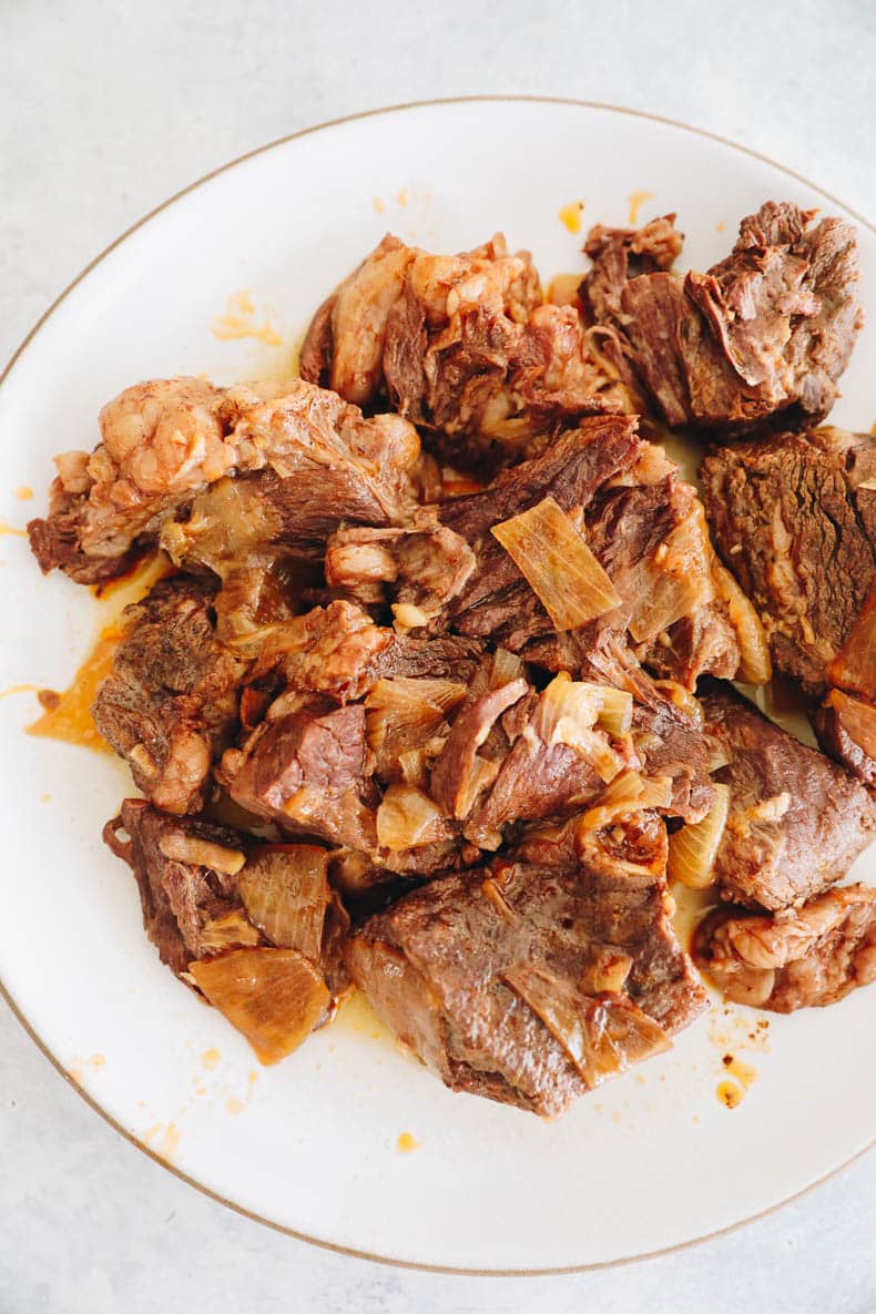 chuck roast cooked and resting on a white plate.