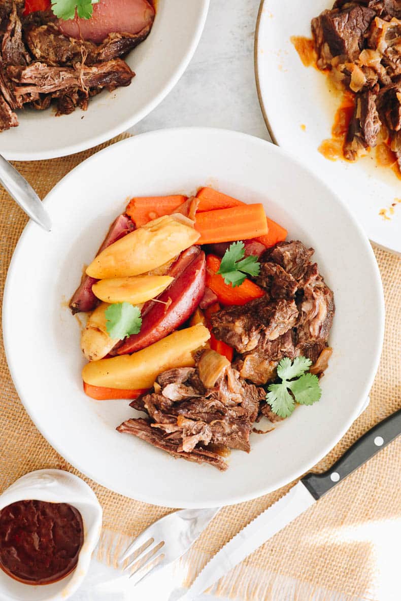 Instant Pot pot roast and potatoes and carrots in a white shallow bowl.