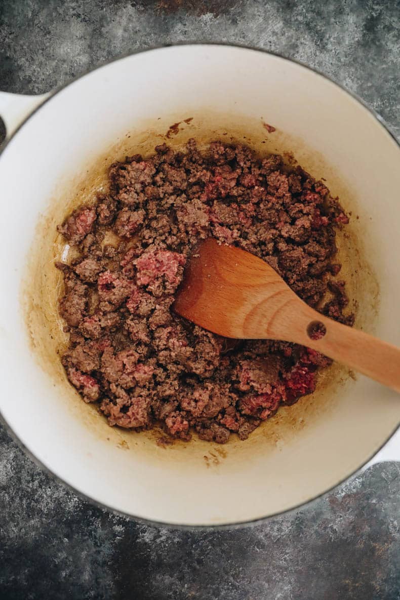 Browned ground beef in a white dutch oven.