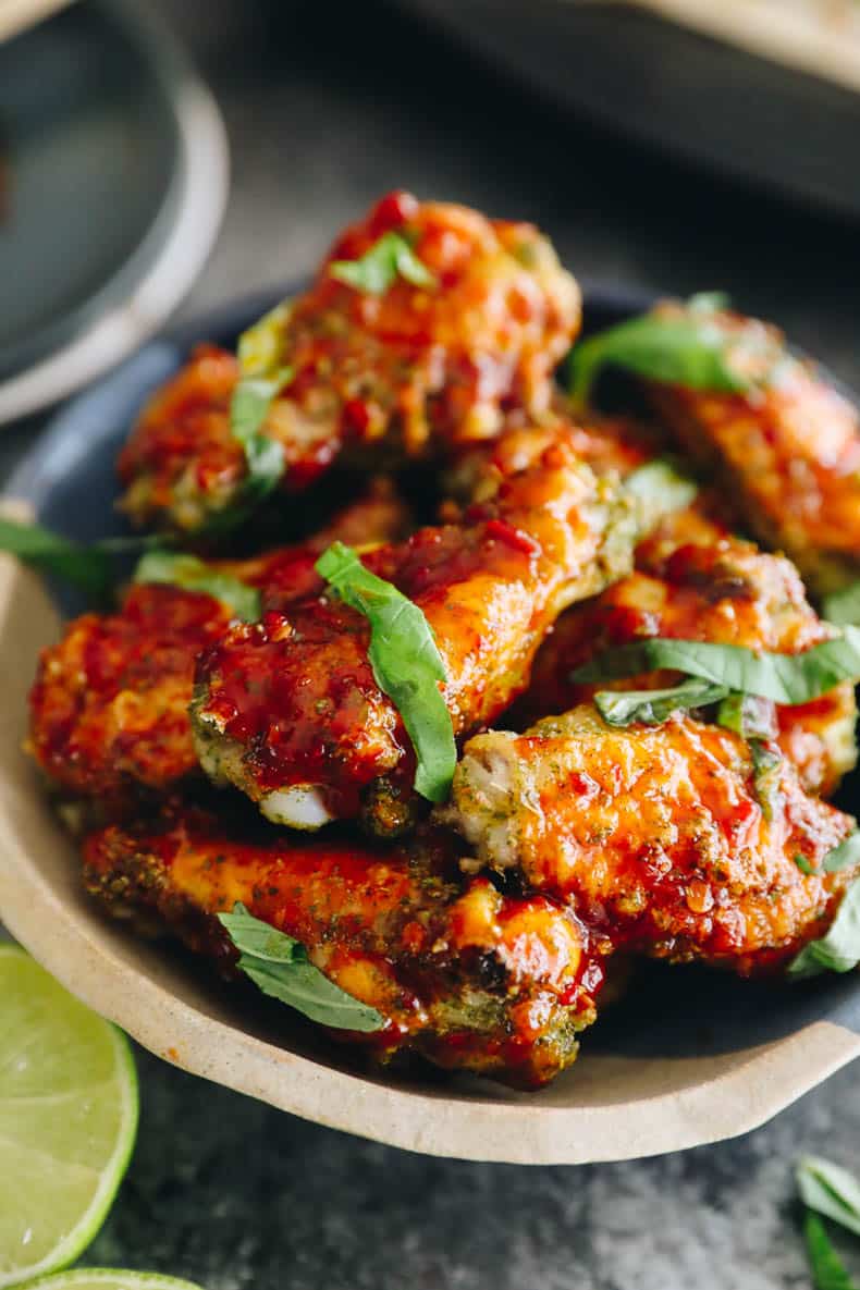 upclose image of baked thai basil wings in a bowl.